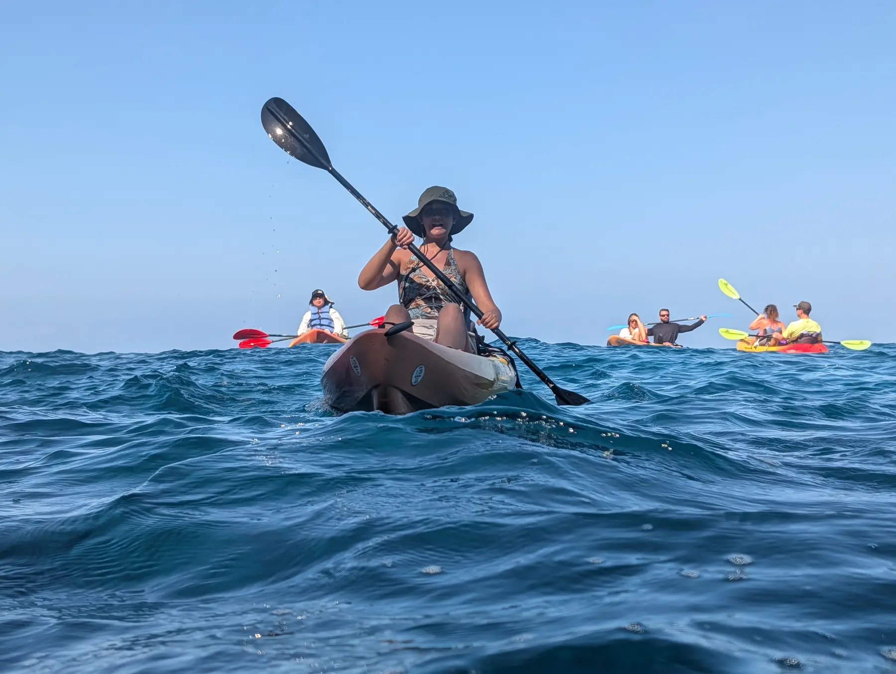 Kayakers paddling across deep blue Pacific water
