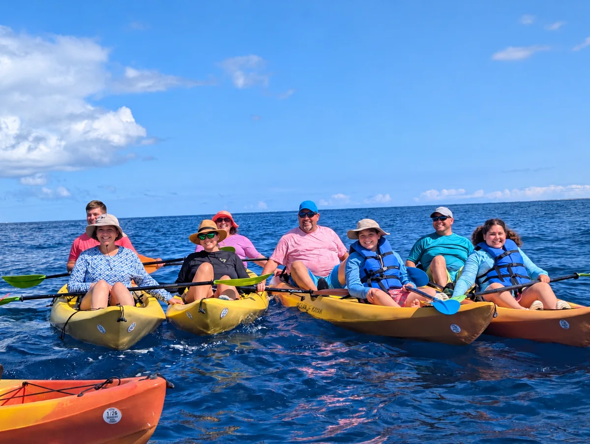 A big, happy group rafted up in kayaks, smiling at the camera