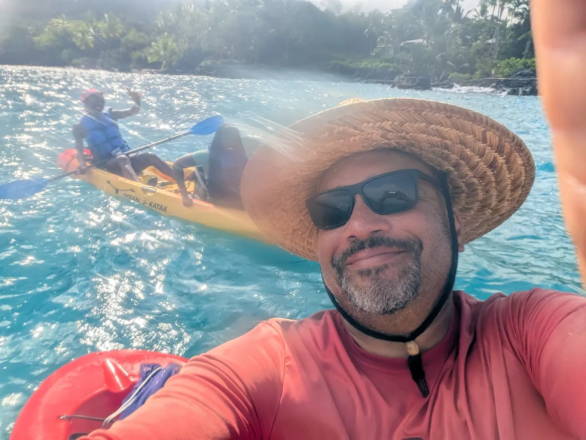 Owner Winfield Brown smiling on the water at Keauhou Bay, with guests paddling behind